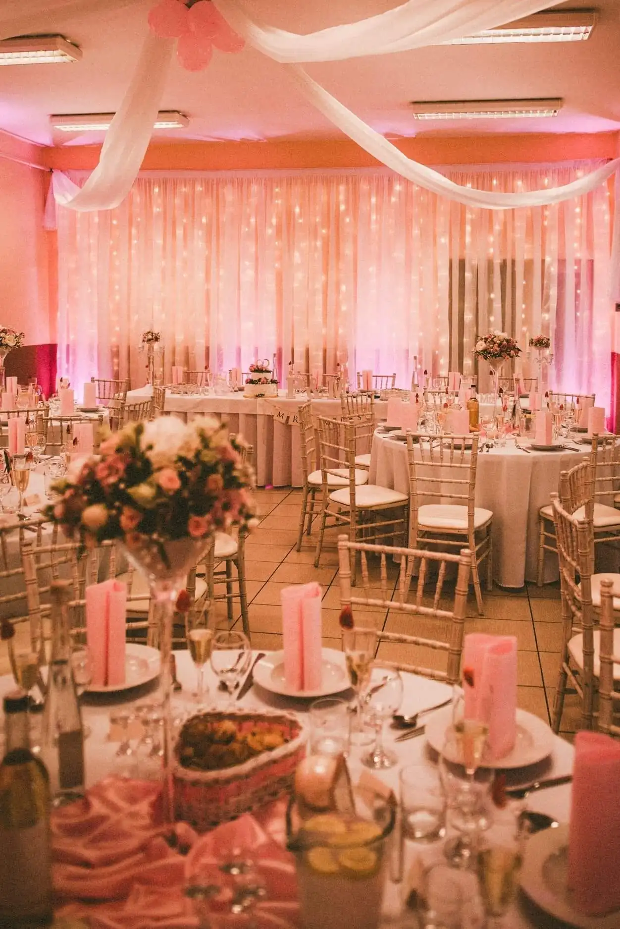 Saal mit runden Tischen und Chiavari-Stühlen in violettem Licht