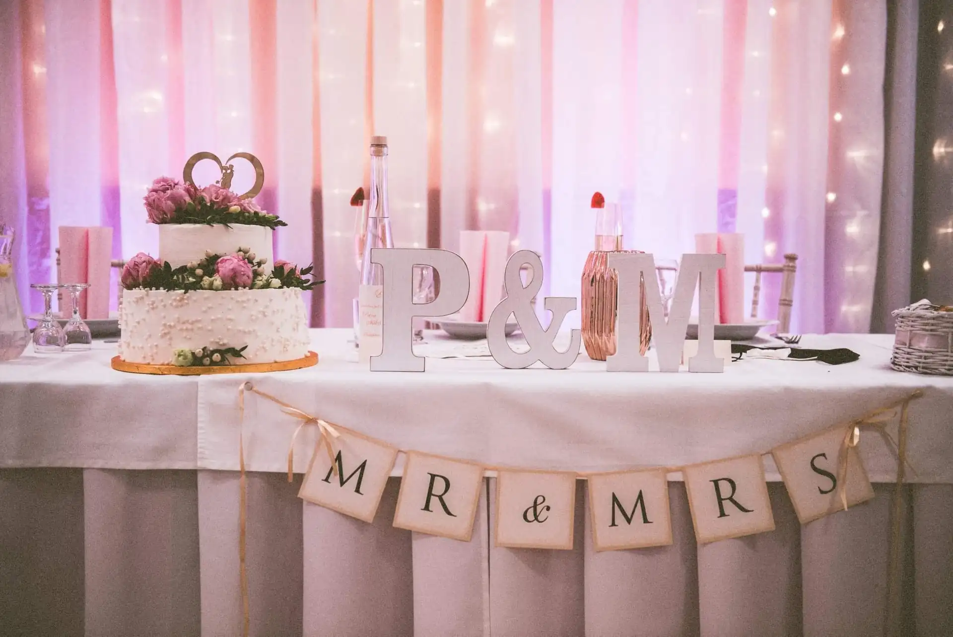 Tisch mit Hochzeitstorte und Girlande mit dem Schriftzug Mr & Mrs